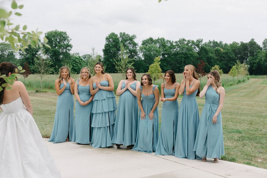 Adisyn’s bridesmaids in dusty blue dresses react as they see her in her wedding gown for the first time
