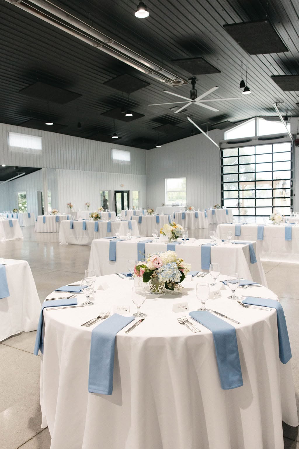 Reception tables at The Grange Hall with white linens, dusty blue napkins and hydrangea centerpieces