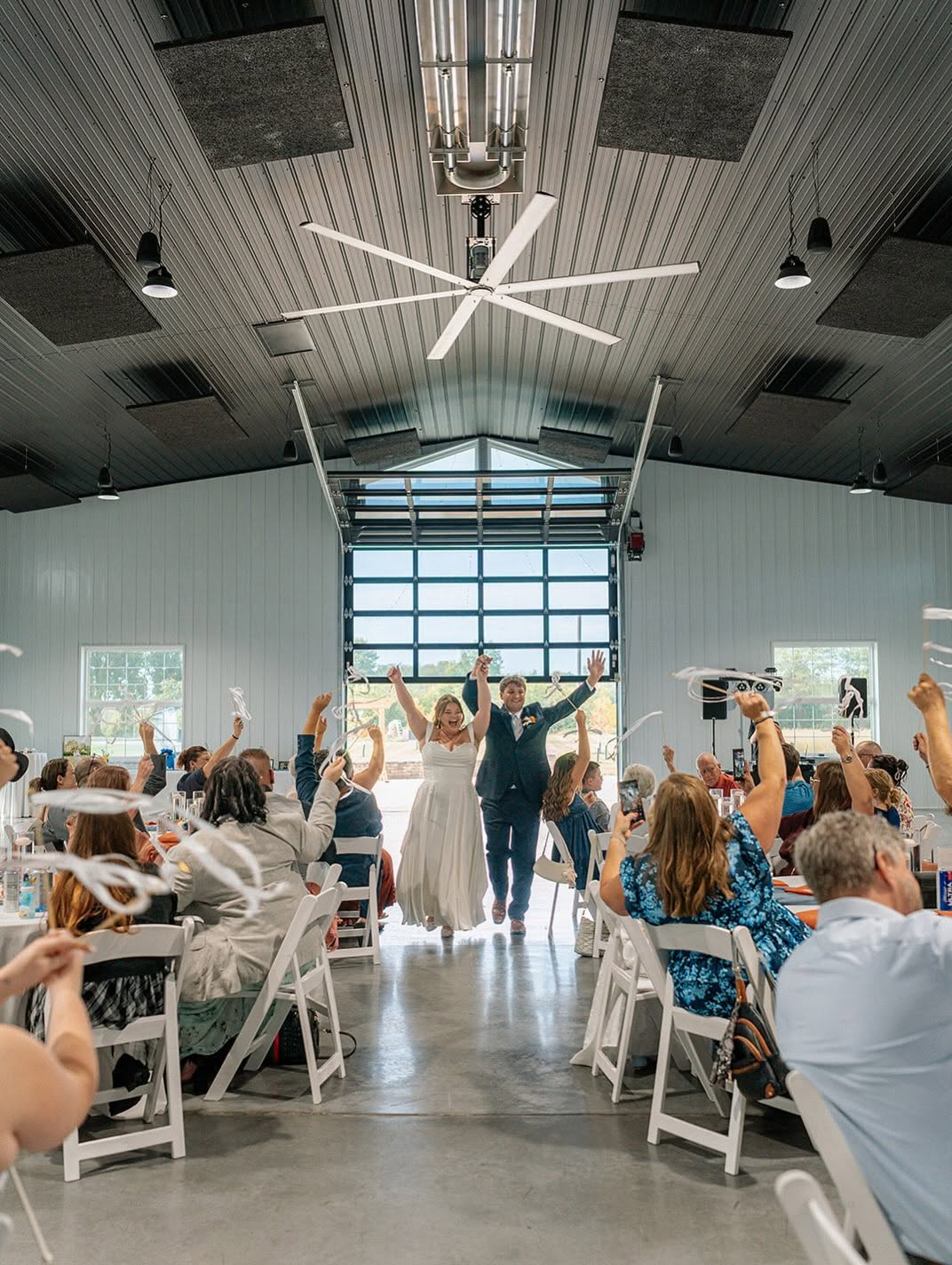 Ashley and Brenton make their grand entrance into The Grange Hall as guests wave ribbon wands