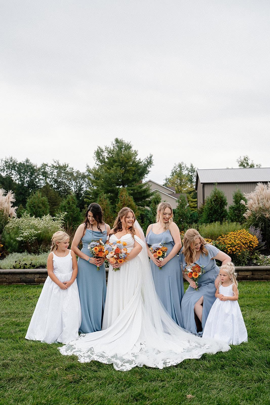 Ashley with her bridesmaids in dusty blue dresses and two flower girls in white in the garden at The Grange Hall