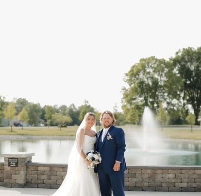 Faith and George pose in front of the pond and fountain at The Grange Hall