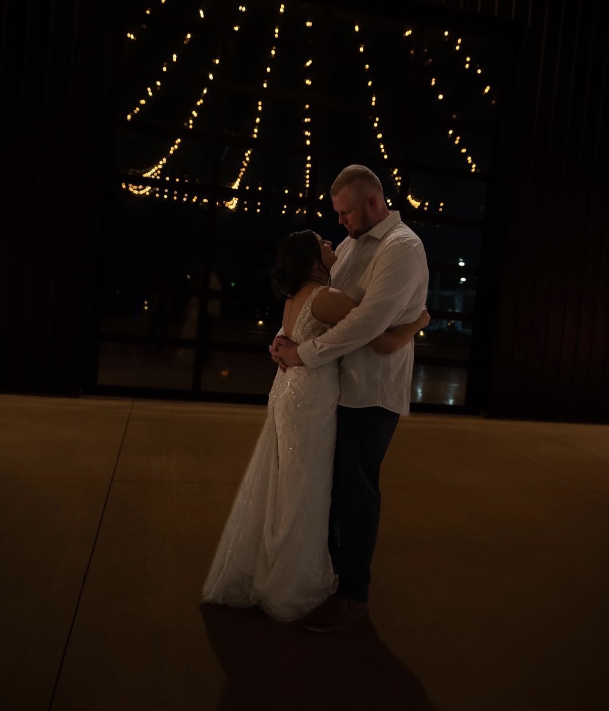 Maddie and Ethan share a dance under string lights inside The Grange Hall